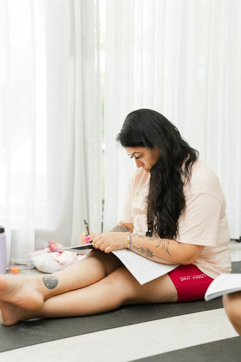 Woman sits comfortably indoors, focused on journaling, promoting mindfulness and relaxation.